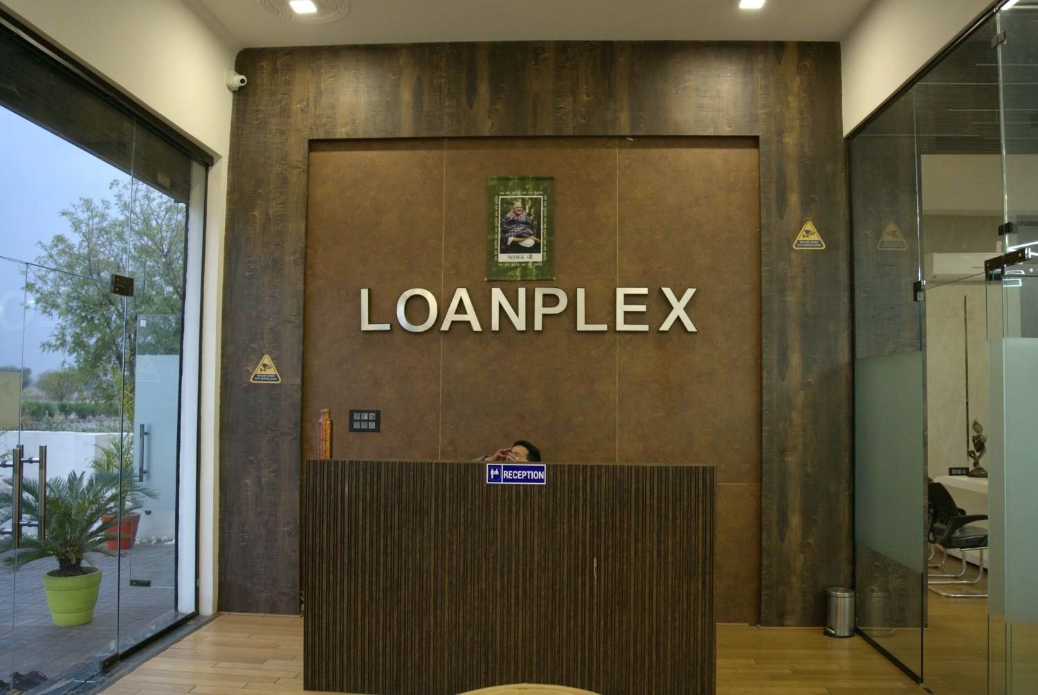 Corporate office interior design Jaipur — Loanplex reception dark textured wall 3D brand lettering curved desk by Endless Interiors